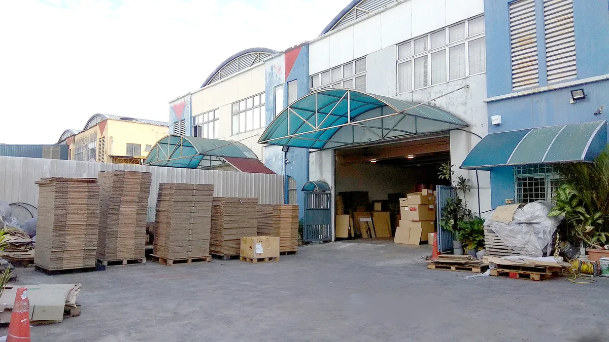 The Quinocycle warehouse in Balakong: an open roller shutter with pallets of flattened carton stacked outside.